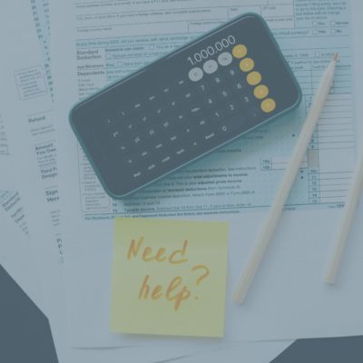 Tax forms with phone calculator and post it note that says "need help?"